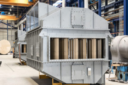 Grote industriële luchtvoorverwarmer in een werkplaats, opgebouwd uit metalen panelen met zichtbare warmtewisselaarbuizen.