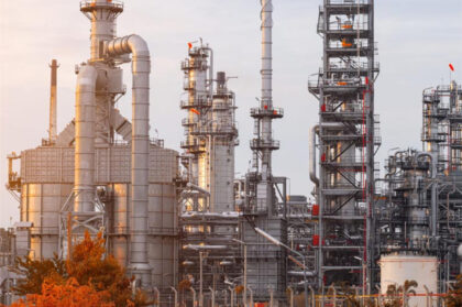 Industrial refinery with complex flue gas installations at sunset.