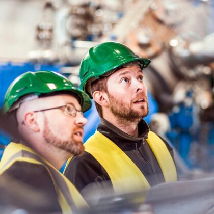 Two technicians with green helmets inspecting an industrial heat recovery system